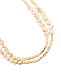 Featuring cream acrylic beaded layered necklace with balls, round stone in beige ivory gold close up view - link has visual effect only