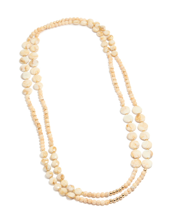 Showcasing cream acrylic beaded layered necklace with balls, round stone disc in beige ivory gold front view