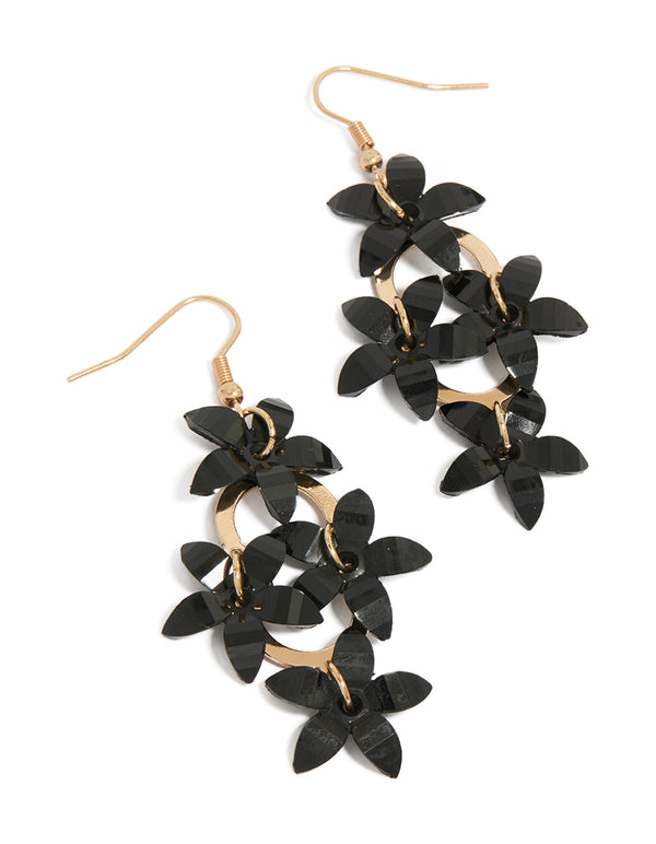 Statement drop earrings featuring four black floral elements connected by gold circular links front view