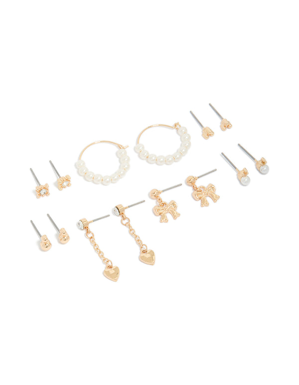 Showcasing a 7-pack of stud earrings featuring bow heart and pearl accents in gold front view