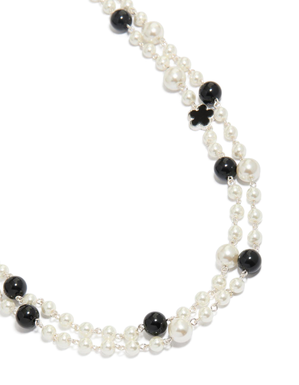 Showcasing a beaded pearl and flower layered necklace in ivory, black, and silver close up view