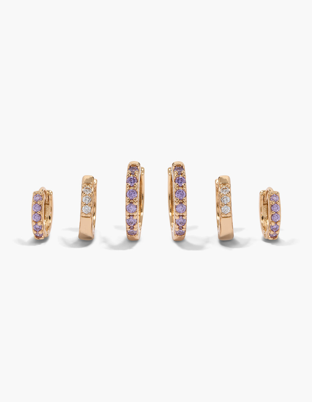 Showcasing a simple huggie earrings 3-pack featuring cubic zirconia in clear and purple stones with gold finish and huggie closure front view